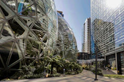 The light reflects off the glass facade of a building on the Amazon campus outside the company headquarter on March 20, 2020, in Seattle.