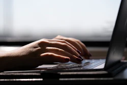 A woman types on a laptop while on a train in New Jersey, May 18, 2021.
