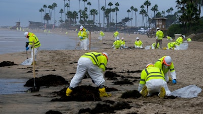 Workers in protective suits clean the contaminated beach in Corona Del Mar after an oil spill in Newport Beach, Calif., Oct. 7, 2021.