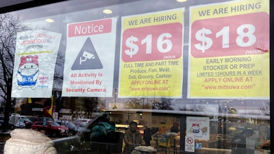 Hiring signs displayed at a grocery store in Arlington Heights, Ill., Jan. 13, 2023.