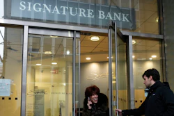 A woman leaves a branch of Signature Bank in New York, March 13, 2023.