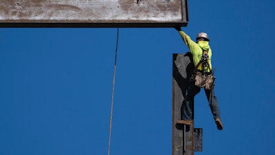 An ironworker guides a beam during construction of a municipal building in Norristown, Pa., Feb. 15, 2023.