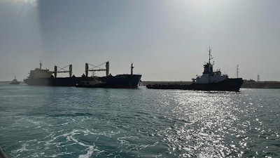 Bulk carrier ship Xin Hai Tong 23, left, is towed after it ran aground at the southern mouth of the Suez Canal, May 25, 2023.