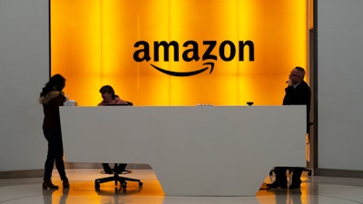 In this Feb. 14, 2019, file photo, people stand in the lobby for Amazon offices in New York.
