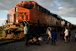 Migrants watch a train go past as they wait along the train tracks hoping to board a freight train heading north, one that stops long enough so they can hop on, in Huehuetoca, Mexico, Sept. 19, 2023.