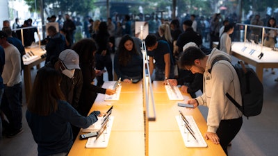 People look at Apple's new iPhone 15 at an Apple Store at The Grove, Los Angeles, Sept. 22, 2023.