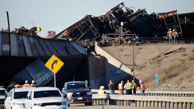 Workers clear cars that derailed in an accident over Interstate 25 north of Pueblo, Colo., Oct. 16, 2023.