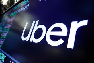 The logo for Uber appears above a trading post on the floor of the New York Stock Exchange, Aug. 16, 2019. The ride-hailing and delivery company said Wednesday, Oct. 4, 2023, that its drivers will collect up to five prepaid and sealed packages and drop them off at a local post office or at UPS or FedEx stores. Uber will charge a flat fee of $5 for the service or $3 for its Uber One members.