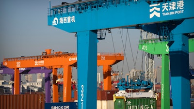 A crane lifts a shipping container at an automated container port in Tianjin, China, Jan. 16, 2023. The global economy, which has proved surprisingly resilient this year, is expected to falter next year under the strain of wars, still-elevated inflation and continued high interest rates.