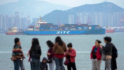 A container ship passes tourists in Xiamen, China, Dec. 26, 2023.