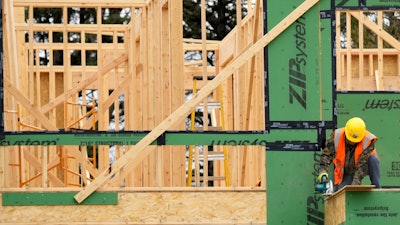 A construction workers cuts wood at a residential building site in Mount Prospect, Ill., March 18, 2024.