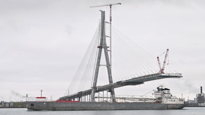 The freighter Manitowoc makes its way down the Detroit River past construction on the Gordie Howe International Bridge, Dec. 29, 2023.