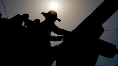 A linesman works on power lines in Phoenix, July 12, 2024.