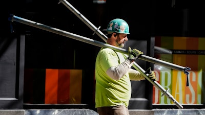 A construction worker carries scaffolding parts, Boston, March 14, 2024.