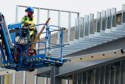 A construction worker maneuvers a lift outside a commercial building site in Mount Prospect, Ill., Tuesday, Aug. 27, 2024.
