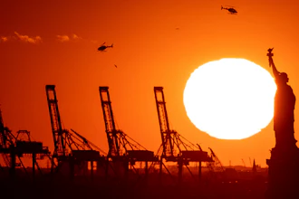 Cranes at the Port of New York and New Jersey appear behind the Statue of Liberty, Nov. 20, 2022.