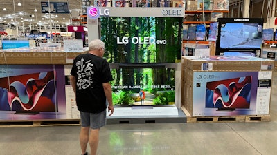 A shopper examines large-screen televisions in a Costco warehouse, Lone Tree, Colo., Sept. 19, 2024.