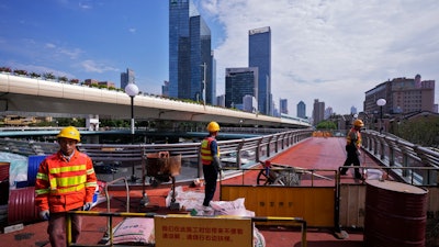 Workers refurbish an overhead pedestrian bridge, Shanghai, Oct. 9, 2024.