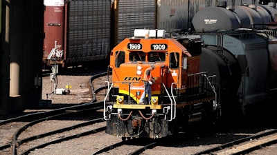 A worker boards a locomotive at a BNSF rail yard, Sept. 14, 2022, Kansas City, Kan.