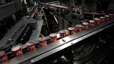 Coca-Cola cans move down a conveyer belt at the Swire Coca-Cola bottling plant, Denver, Oct. 20, 2023.