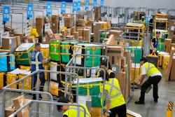 Amazon employees load packages on carts at an Amazon DAX7 delivery station, July 16, 2024, South Gate, Calif.