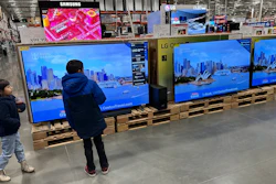 Young shoppers look over a row of large-screen televisions in a Costco warehouse, Denver, Dec. 19, 2024.