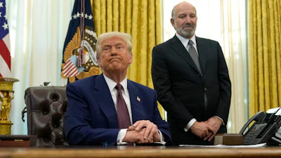 President Donald Trump listens to a question from a reporter as Commerce Secretary nominee Howard Lutnick watches after Trump signed an executive order in the Oval Office of the White House, Thursday, Feb. 13, 2025, in Washington.