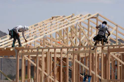Construction workers frame up a roof of wood lumber at a new home build, April 1, 2025, in Laveen, Ariz.