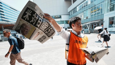 A staff member distributes an extra edition of the Yomiuri Shimbun newspaper, which reads, 'U.S., a 15% tax on goods imported from Japan,' July 23, 2025, Tokyo.