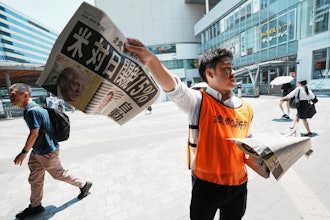 A staff member distributes an extra edition of the Yomiuri Shimbun newspaper, which reads, 'U.S., a 15% tax on goods imported from Japan,' July 23, 2025, Tokyo.