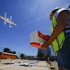 Masslie Arias, of DoorDash, prepares to load a delivery package on a hovering drone Thursday, July 31, 2025, in Frisco, Texas.