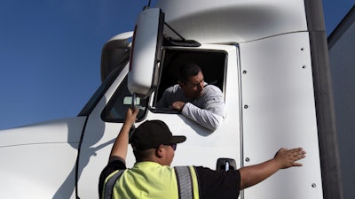 Senior instructor Markus Juarez, bottom, talks to student driver Jaime Rojas at California Truck Driving Academy, Inglewood, Calif., Nov. 17, 2021.