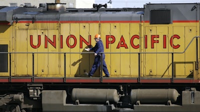 A maintenance worker walks past a locomotive in the Union Pacific Railroad fueling yard in north Denver, Oct. 18, 2006.