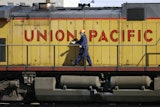 A maintenance worker walks past a locomotive in the Union Pacific Railroad fueling yard in north Denver, Oct. 18, 2006.