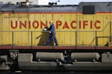 A maintenance worker walks past a locomotive in the Union Pacific Railroad fueling yard in north Denver, Oct. 18, 2006.