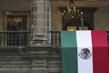 A Mexican flag hangs at the National Palace, where a portrait of former Mexico President Andres Manuel Lopez Obrador hangs, as President Claudia Sheinbaum delivers her first state-of-the-nation address in Mexico City, Monday, Sept. 1, 2025.