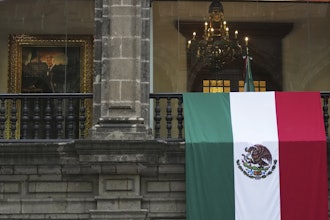 A Mexican flag hangs at the National Palace, where a portrait of former Mexico President Andres Manuel Lopez Obrador hangs, as President Claudia Sheinbaum delivers her first state-of-the-nation address in Mexico City, Monday, Sept. 1, 2025.