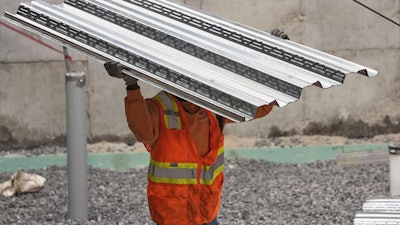 A construction worker carries steel decking at a construction site, Portland, Maine, July 31, 2025.