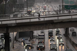 A pedestrian with an umbrella walks on a bridge over the rain-soaked 110 Freeway in Los Angeles, Nov. 14, 2025.