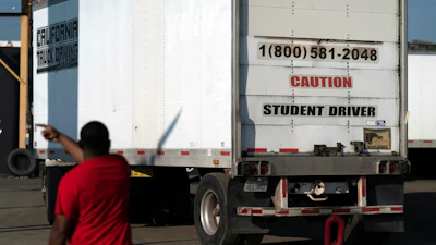 A student driver helps his classmate steer the wheel into the right direction as they practice driving in reverse, Nov. 17, 2021.