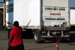 A student driver helps his classmate steer the wheel into the right direction as they practice driving in reverse, Nov. 17, 2021.