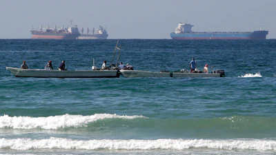 Fishermen work in front of oil tankers south of the Strait of Hormuz, Jan. 19, 2012, off Ras Al Khaimah, United Arab Emirates.