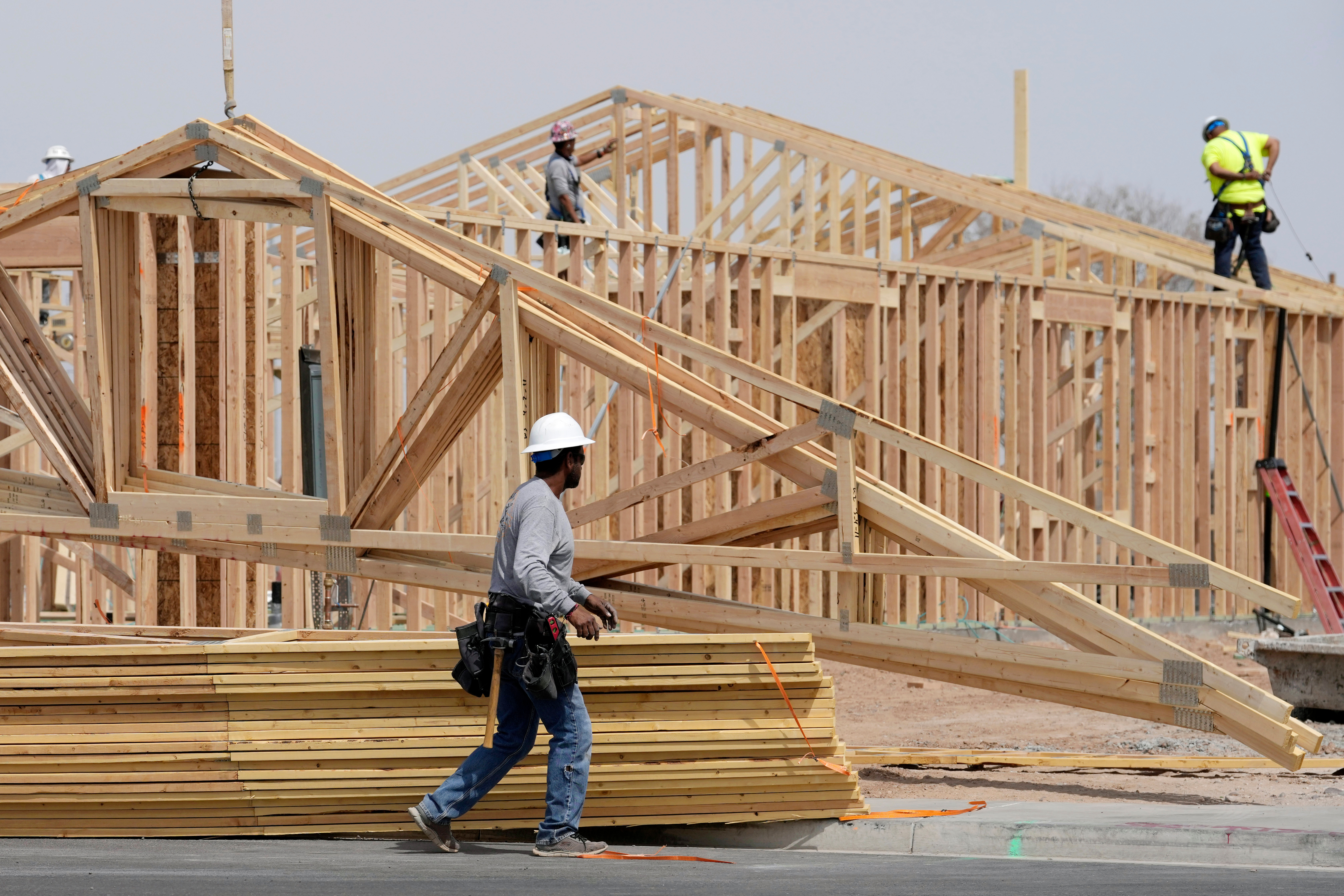 Construction workers install a lumber roof at a new home build, April 1, 2025, Laveen, Ariz.