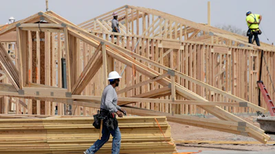 Construction workers install a lumber roof at a new home build, April 1, 2025, Laveen, Ariz.