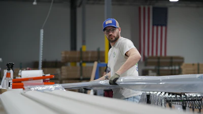 A worker lifts an aluminum beam on the factory floor at The Luxury Pergola, a company that manufactures aluminum pergolas, on Friday, Feb. 20, 2026, in Noblesville, Ind.