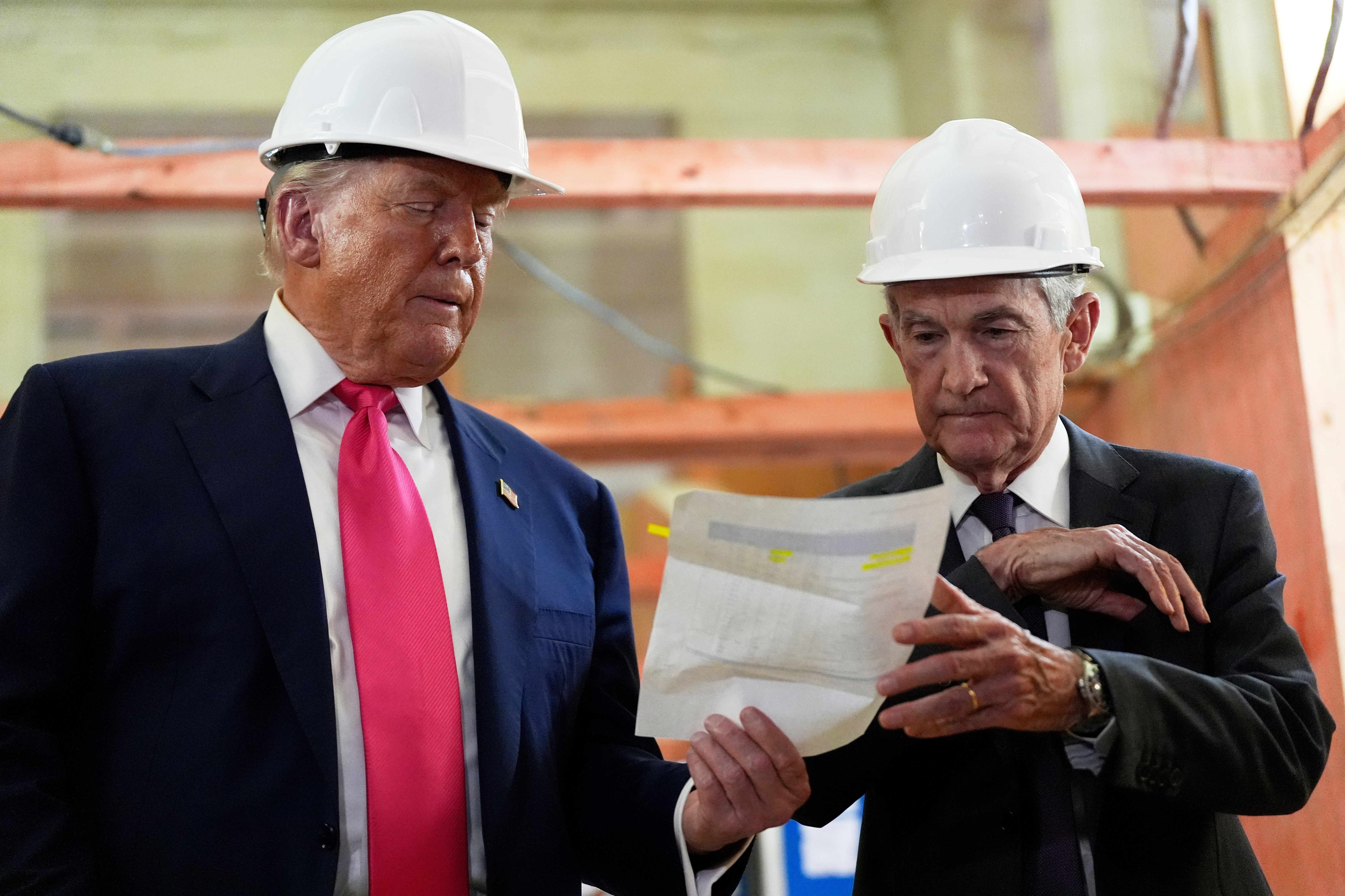 Federal Reserve Chairman Jerome Powell, right, and President Donald Trump look over a document during a visit to the Federal Reserve, July 24, 2025, Washington.