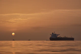 The sun rises behind tankers anchored in the Strait of Hormuz off the coast of Qeshm Island, Iran, April 18, 2026.