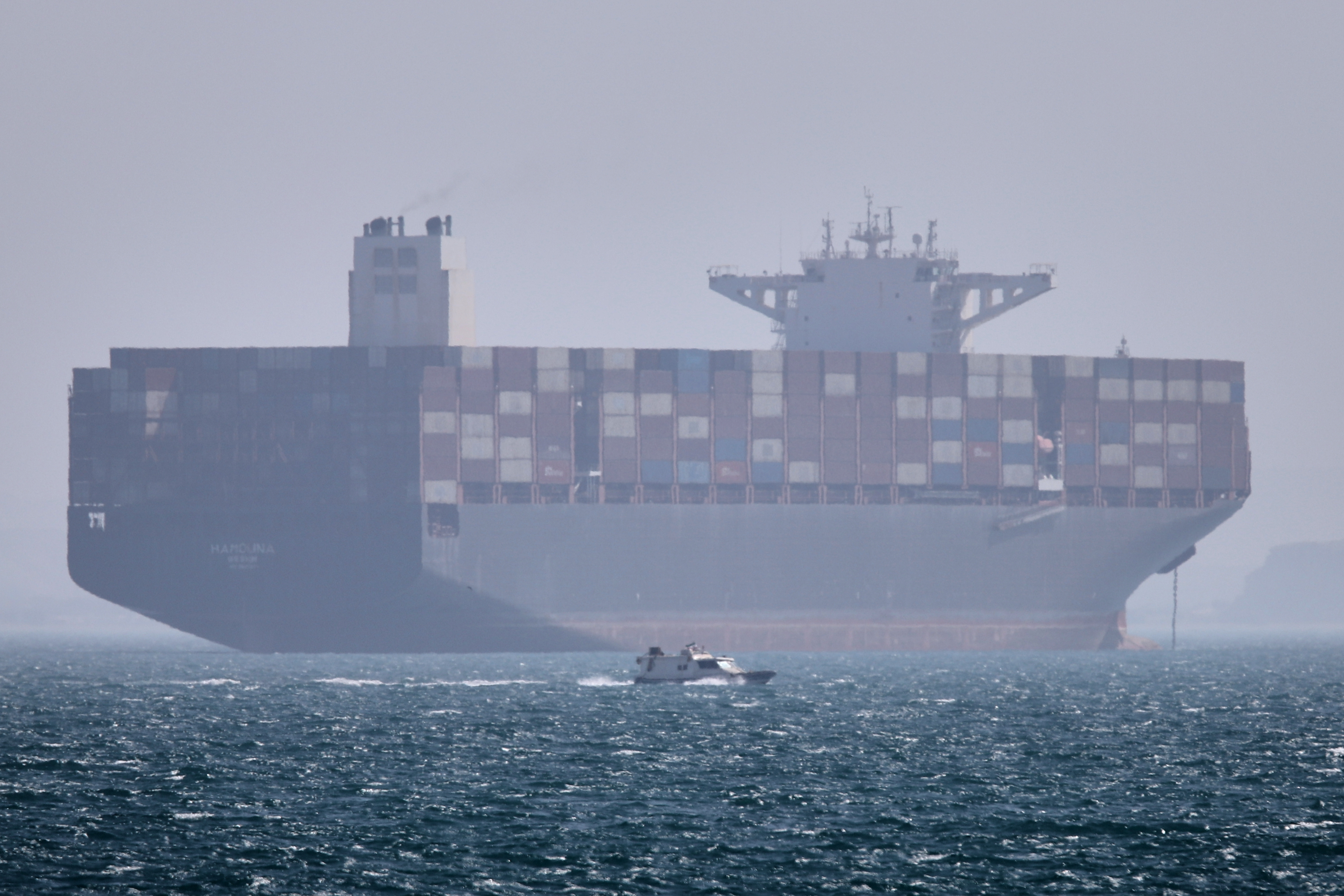 A container ship sits at anchor as a small motorboat passes in the Strait of Hormuz off Bandar Abbas, Iran, May 2, 2026.