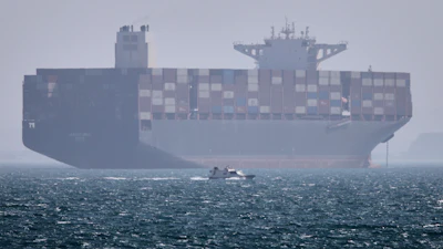 A container ship sits at anchor as a small motorboat passes in the Strait of Hormuz off Bandar Abbas, Iran, May 2, 2026.