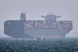 A container ship sits at anchor as a small motorboat passes in the Strait of Hormuz off Bandar Abbas, Iran, May 2, 2026.